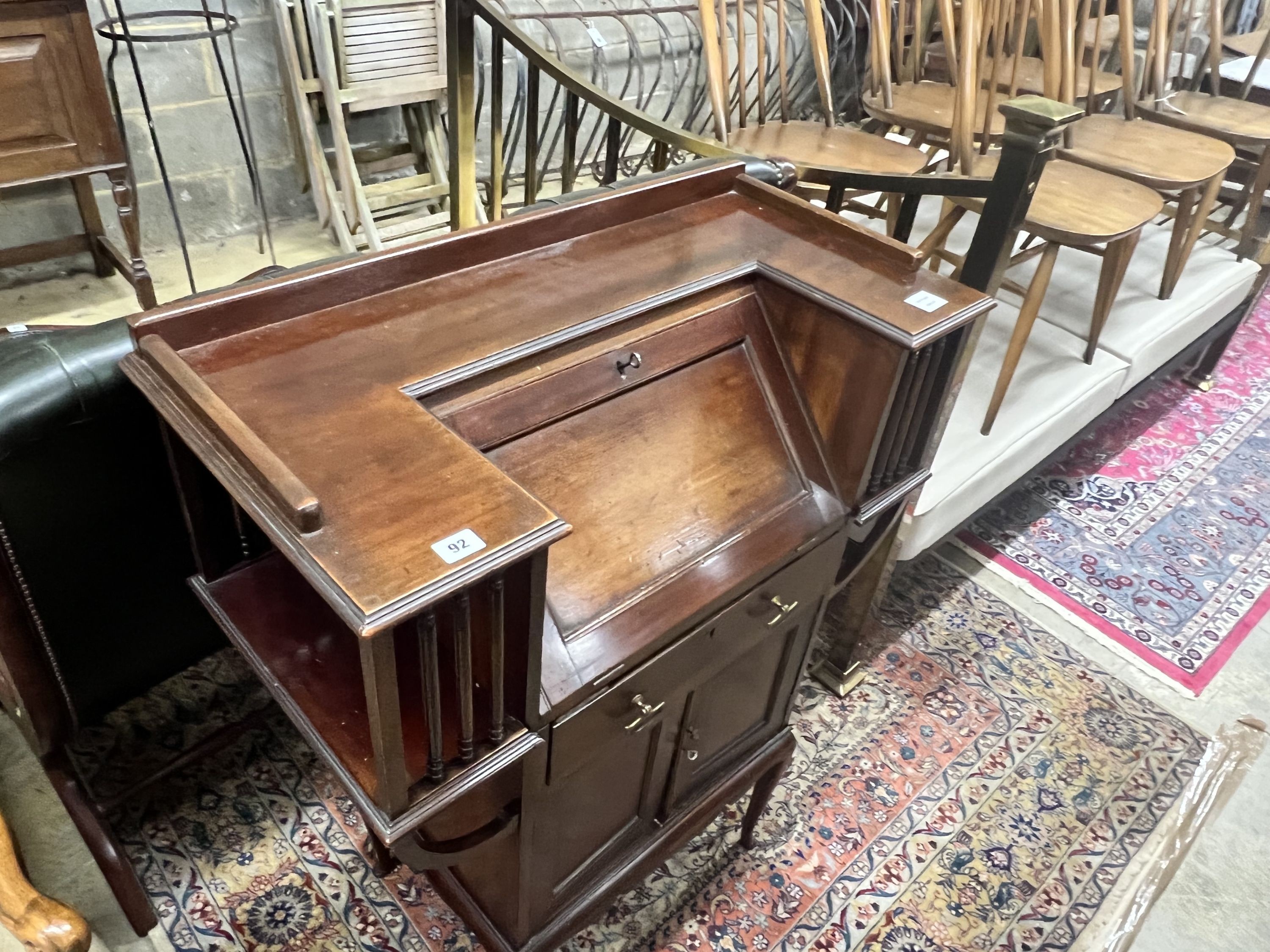 A late Victorian mahogany bureau, rectangular top with moulded ledge back and inset panelled writing slope, projecting bookshelves to the sides spaced with turned supports‘ drawers and cupboard doors, on cabriole support